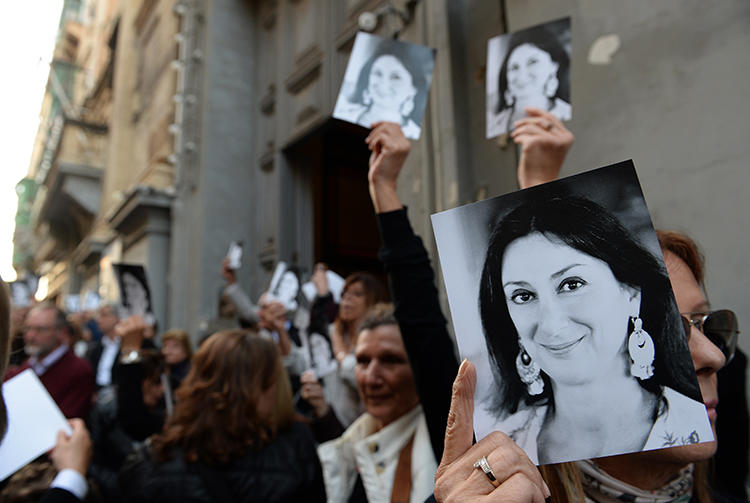 People are seen holding photos of journalist Daphne Caruana Galizia in Valletta, Malta, on April 16, 2018. The Parliamentary Assembly of the Council of Europe recently passed a resolution requiring the Maltese government to launch an independent public inquiry into her killing. (AFP/Matthew Mirabelli)