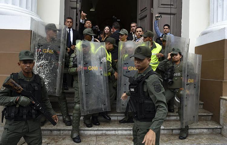 Miembros de la Guardia Nacional Bolivariana impiden a los periodistas entrar a la Asamblea Nacional, en Caracas, Venezuela, el 18 de junio de 2019. Los oficiales han bloqueado la entrada de los periodistas al edificio de la Asamblea durante los debates celebrados los días martes, desde el 7 de mayo. (AFP/Yuri Cortez)