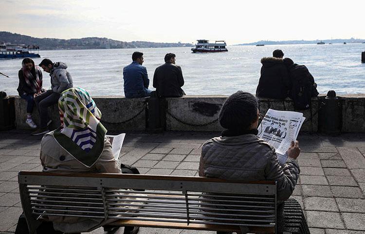 People read papers by the Bosporus in Istanbul in April 2019. A journalist this week started a prison sentence for insulting Turkey's president in a speech. (AP/Emrah Gurel)