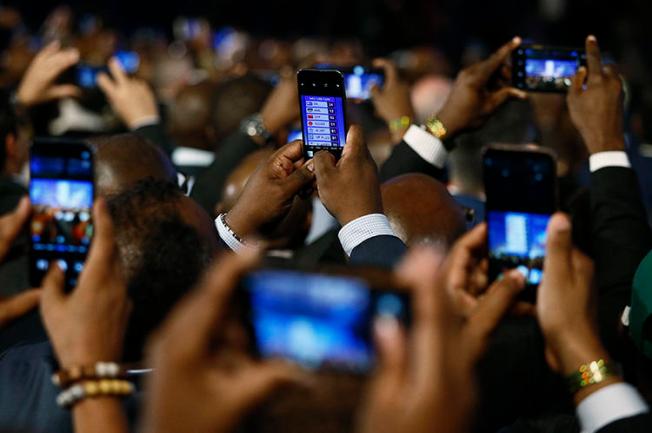 People take pictures with cells phones during the formal announcement of election results in Pretoria on May 11. Journalists covering the election had to contend with online harassment, doxxing, and threats. (AFP/Phill Magakoe)