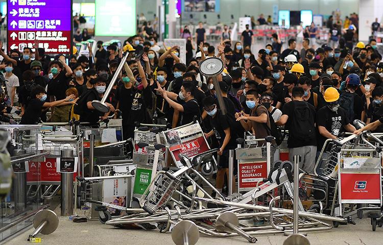 Pro-democracy protesters block the entrance to the airport terminals at Hong Kong's international airport on August 13, 2019. The protesters that day assaulted a journalist from China’s Global Times at the airport. (AFP/Manan Vatsyayana)