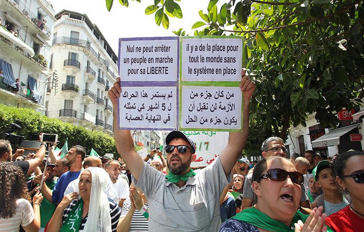 A man holds a placard reading "no one can stop a people marching for his freedom" as Algerian protesters demonstrate in Algiers on July 26, 2019. Access to at least five independent local news websites has been interrupted in recent weeks amid the protests. (AFP)