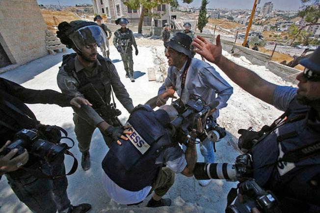 A picture taken in Dar Salah on August 2 shows Israeli border police scuffling with a journalist. At least 3 journalists were injured covering protests in Gaza and the West Bank on August 2. (AFP/Musa Al-Shaer)