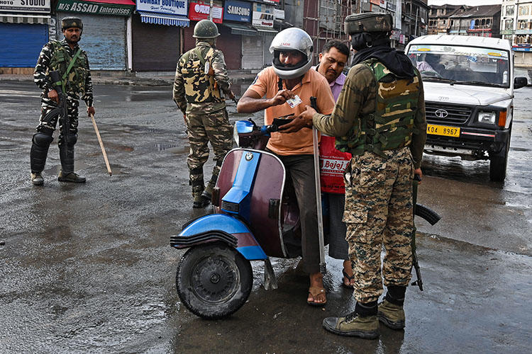 Indian security personnel check the identity of a motorist during a curfew in Srinagar on August 8, 2019, as widespread restrictions on movement and a telecommunications blackout are in place after the Indian government stripped Jammu and Kashmir of its autonomy. (AFP/Tauseef Mustafa)