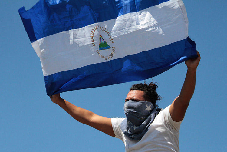 AUn manifestante despliega una bandera de Nicaragua en Managua, el 16 de marzo de 2019.  Periodistas que cubrían protestas antigubernamentales a lo largo del país fueron atacados, acosados y, en algunos casos, detenidos. (AFP/Maynor Valenzuela)