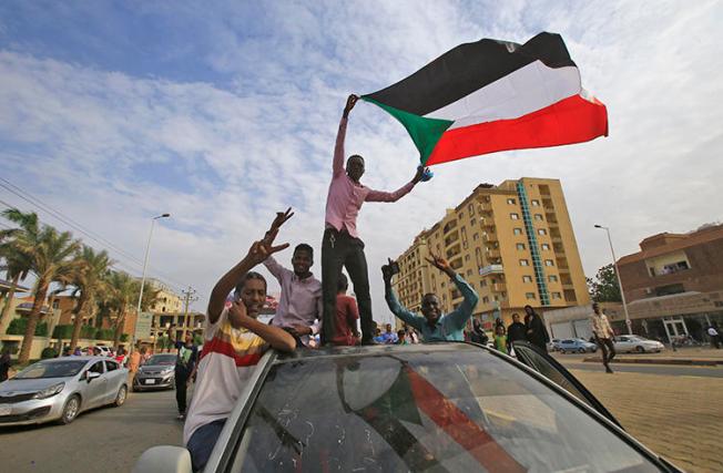 Sudanese protesters wave the national flag during a demonstration in the capital Khartoum on August 1, 2019. On July 24, authorities detained Al-Sayha newspaper editor-in-chief and journalists’ union head Sadiq al-Rizaigi. (AFP/Ashraf Shazly)