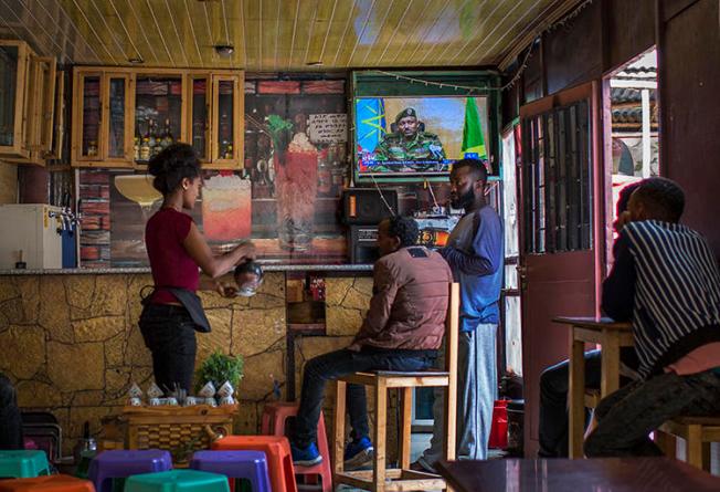 Ethiopians follow the news on television at a cafe in Addis Ababa, Ethiopia Sunday, June 23, 2019. Ethiopian authorities arrested journalist Mesganaw Getachew on August 9 after he filmed outside a court in Addis Ababa. (AP Photo/Mulugeta Ayene)