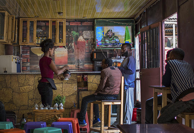 Ethiopians follow the news on television at a cafe in Addis Ababa, Ethiopia Sunday, June 23, 2019. Ethiopian authorities arrested journalist Mesganaw Getachew on August 9 after he filmed outside a court in Addis Ababa. (AP Photo/Mulugeta Ayene)