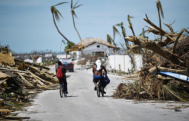 Residents pass damage caused by Hurricane Dorian on September 5, 2019, in Marsh Harbour, Great Abaco Island in the Bahamas. (AFP/Brendan Smialowski)