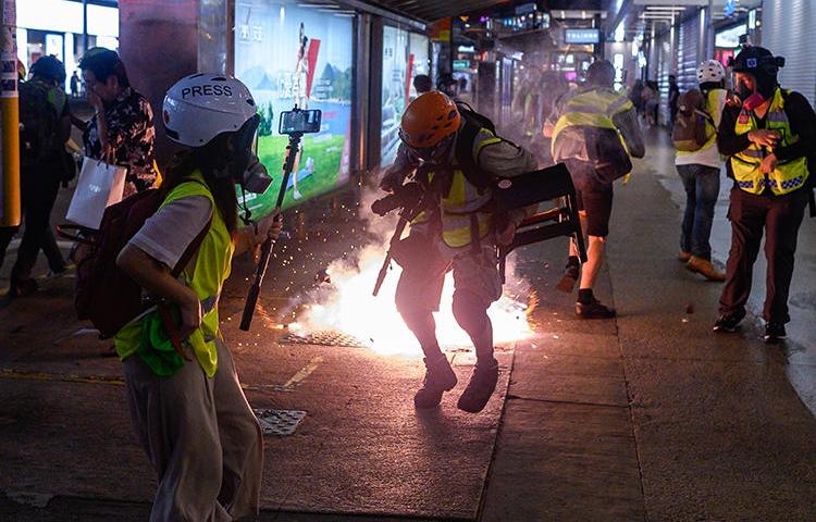 Journalists react as police fire tear gas in Hong Kong on September 8, 2019. Police recently fired tear gas and pepper spray at several groups of journalists covering protests in the city. (AFP/Philip Fong)