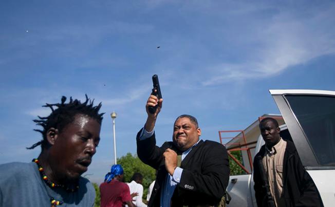 Le Sénateur Jean Marie Ralph Féthière fait feu avec son arme à Port-au-Prince, Haïti, le 23 septembre 2019. Le photographe de l’AP Chery Dieu-Nalio a été blessé par le tir au cours de l’incident. (AP/Chery Dieu-Nalio)