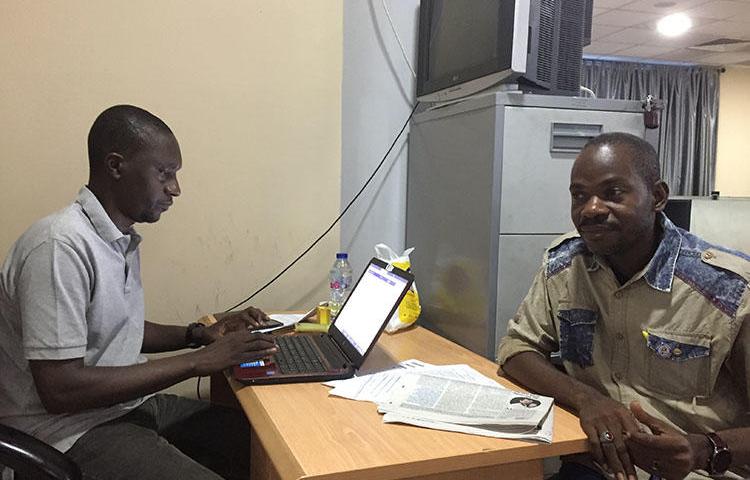 Hamza Idris (left), an editor with the Daily Trust newspaper, sits with colleague Hussaini Garba Mohammed in their office in the Nigerian capital, Abuja, in February 2019. The office was raided in January by the military, who seized 24 computers. (CPJ/Jonathan Rozen)