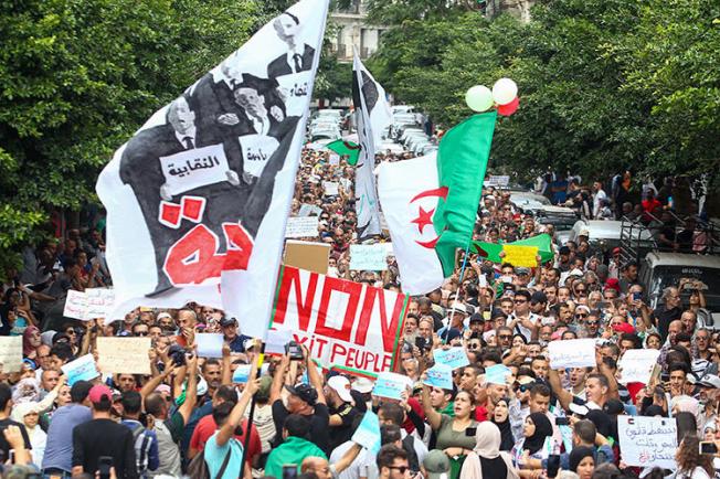 Algerian demonstrators chant and wave their country's national flag as they take part in an anti-government protest in the capital Algiers on October 15, 2019. Authorities have detained at least three more journalists in recent days. (AFP)