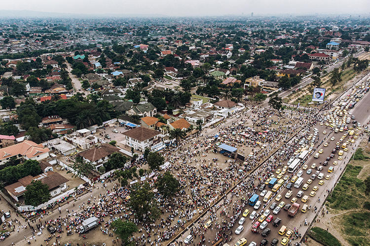 An aerial view shows a crowd gathered outside the Union for Democracy and Social Progress (UDPS) headquarters in Kinshasa on May 30, 2019, as supporters await the return of the remains of former Congolese Prime Minister and opposition leader Etienne Tshisekedi, who died in Belgium in 2017. A Congolese radio journalist was attacked by UDPS supporters at a Kinshasa rally on October 5, 2019. (AFP/Alexis Huguet)