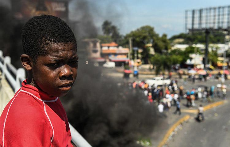 A boy looks on as protesters demand the resignation of President Jovenel Moïse in Port-au-Prince, on October 4. A radio journalist who had been critical of the unrest and who was threatened over his reporting, was killed Mirebalais in October. (AFP/Chandan Khanna)