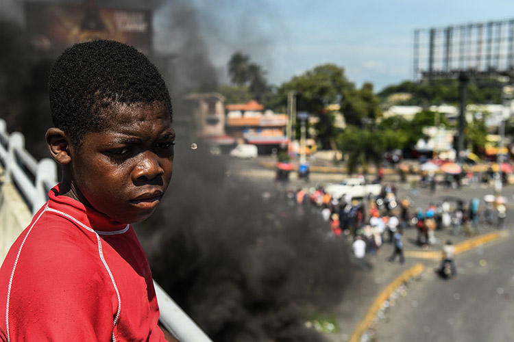 A boy looks on as protesters demand the resignation of President Jovenel Moïse in Port-au-Prince, on October 4. A radio journalist who had been critical of the unrest and who was threatened over his reporting, was killed Mirebalais in October. (AFP/Chandan Khanna)