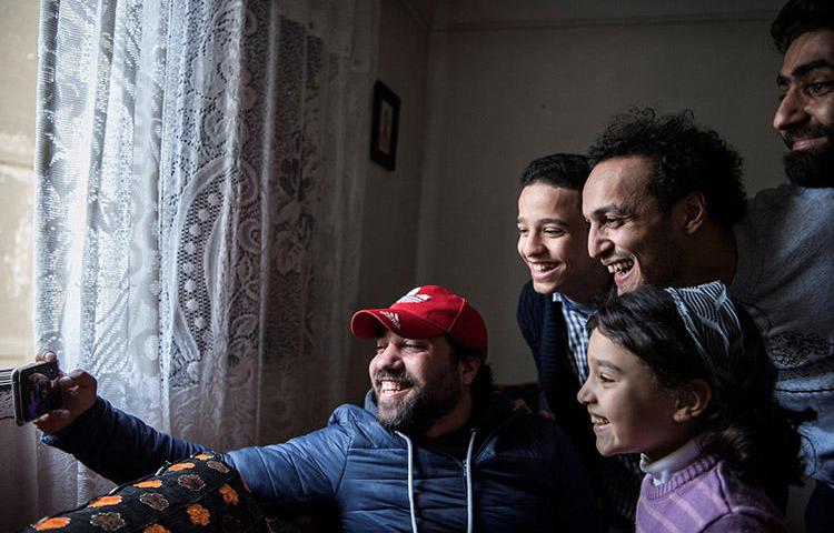The Egyptian photojournalist Mahmoud Abu Zeid, second right, known as Shawkan, poses for a selfie at his home in Cairo on March 4, 2019. As part of the restrictive terms of his release from prison, the journalist has to spend each night at a police station. (AFP/Khaled Desouki)