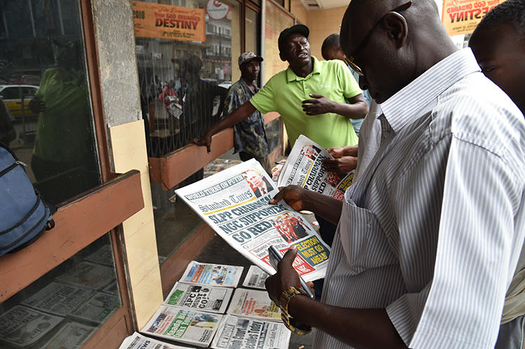 A man reads headlines of a daily newspaper on March 27, 2018, in Freetown. A freelance journalist was charged with criminal defamation in Sierra Leone in September 2019. (AFP/Issouf Sanogo)