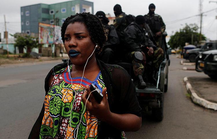 A woman walks past Rapid Intervention Battalion members as they patrol in the city of Buea in October 2018. CPJ and others are calling on the ACHPR to address human rights violations in Cameroon's Anglophone regions. (Reuters/Zohra Bensemra)