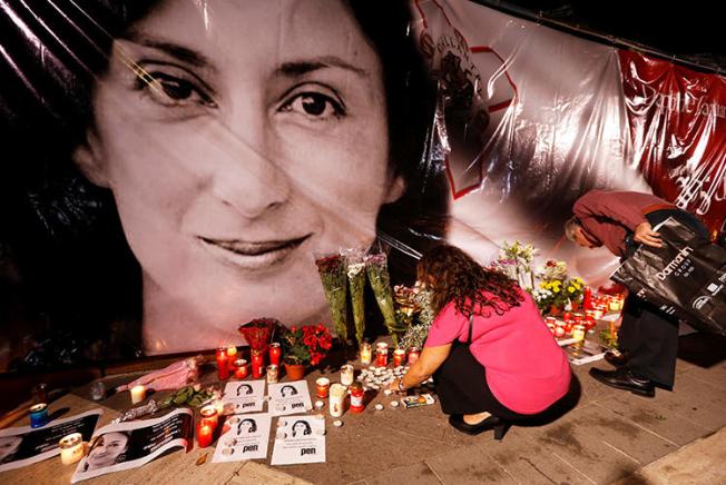 People lay flowers and candles at a memorial during a vigil and protest on the first anniversary of the assassination of journalist Daphne Caruana Galizia outside the Courts of Justice in Valletta, Malta, on October 16, 2018. On the second anniversary of her murder, CPJ joined a call to end impunity in her case. (Reuters/Darrin Zammit Lupi)