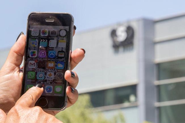 An Israeli woman uses her iPhone in front of the building housing the Israeli NSO group, on August 28, 2016, in Herzliya, near Tel Aviv. NSO Group has been accused of facilitating surveillance of journalists through sales of its Pegasus spyware. (AFP/Jack Guez)