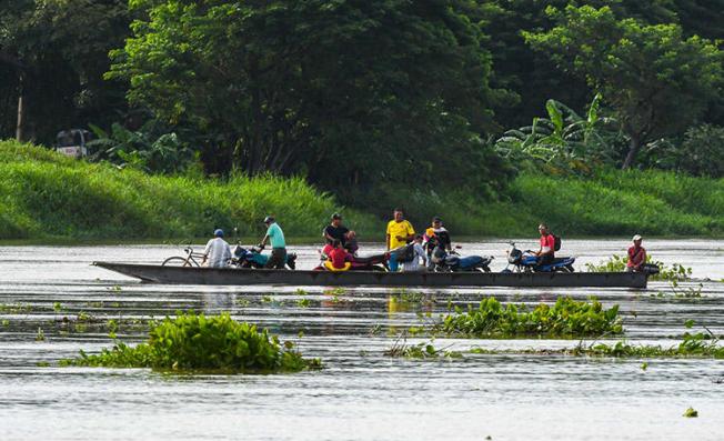 Un grupo de personas transportan motocicletas en una lancha por el río Magdalena en Santa Cruz de Mompox, Colombia, en septiembre de 2017. Atacantes prendieron fuego a una lancha que un periodista en Simití utilizaba para informar sobre comunidades remotas a lo largo del río. (AFP / Luis Acosta)