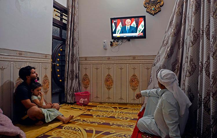 People watch television in Najaf, Iraq, on October 31, 2019. Iraq's media regulator recently ordered the closure of 12 broadcast outlets throughout the country. (AFP/Haidar Hamdani)