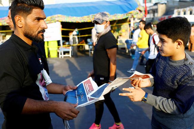 A demonstrator distributes a newspaper in Baghdad, Iraq, on November 17, 2019. A journalist was recently abducted and a broadcaster's office attacked amid the demonstrations. (Reuters/Thaier al-Sudani)