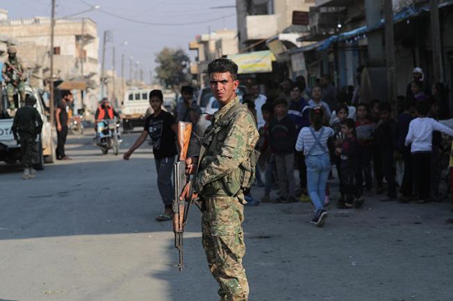 A Turkey-backed Syrian rebel fighter stands in a street in the border town of Tal Abyad, in Syria, on October 27, 2019. Military action in Syria has increased risks for journalists. (Reuters/Khalil Ashawi)