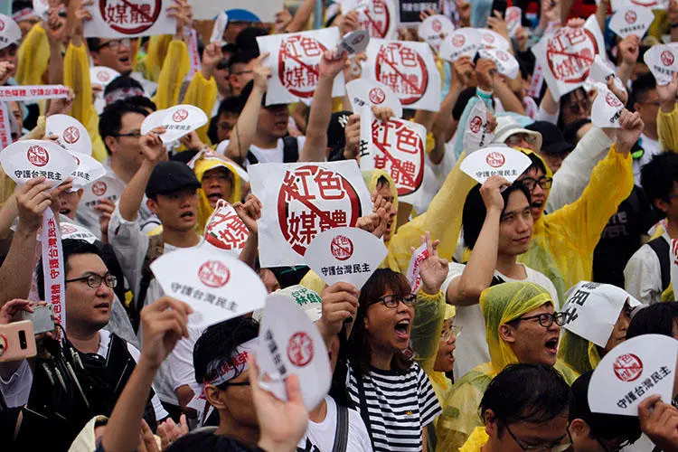 In this photo taken on June 23, 2019, protesters hold placards with messages that read 'reject red media' and 'safeguard the nation's democracy' during a rally against pro-China media in front of the Presidential Office building in Taipei. (AFP/Hsu Tsun-hsu)