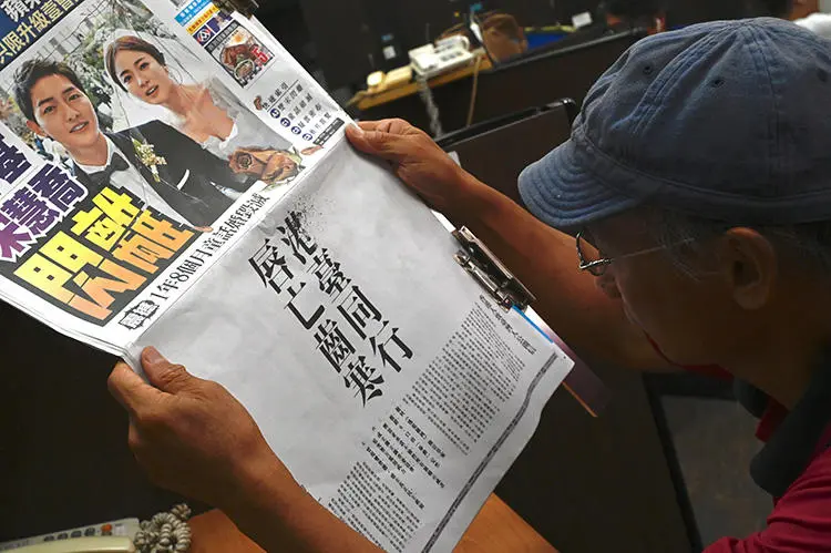 A journalist reads an advert placed in the Apple Daily newspaper in Taipei on June 28, 2019, placed by a Hong Kong campaign group calling for solidarity with Hong Kong protesters demanding the withdrawal of a bill that would allow extraditions to the Chinese mainland. (AFP/Sam Yeh)