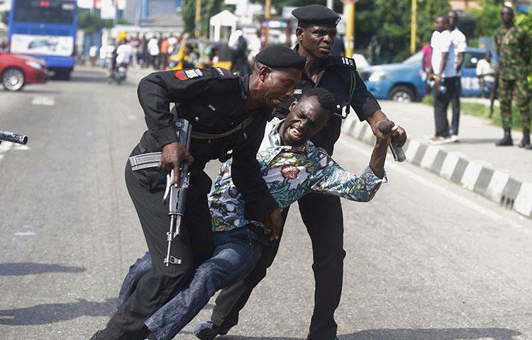 Police officers detain Sahara Reporters journalist Victor Ogungbenro during a protest in Lagos, Nigeria, on August 5, 2019. Staff at the online newspaper report sustained harassment targeting them and their website. (AP/Sunday Alamba)