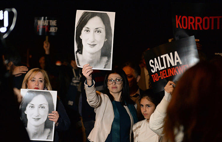 Protesters hold pictures of murdered Maltese journalist Daphne Caruana Galizia as they gather outside the prime minister's office in Valletta, Malta, on November 20, 2019. (AFP/Matthew Mirabelli)