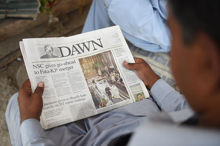 A man reads a copy of the Dawn English-language newspaper in Karachi, Pakistan, on May 20, 2018. Demonstrators recently besieged Dawn's Islamabad offices and threatened its staffers. (AFP/Rizwan Tabassum)