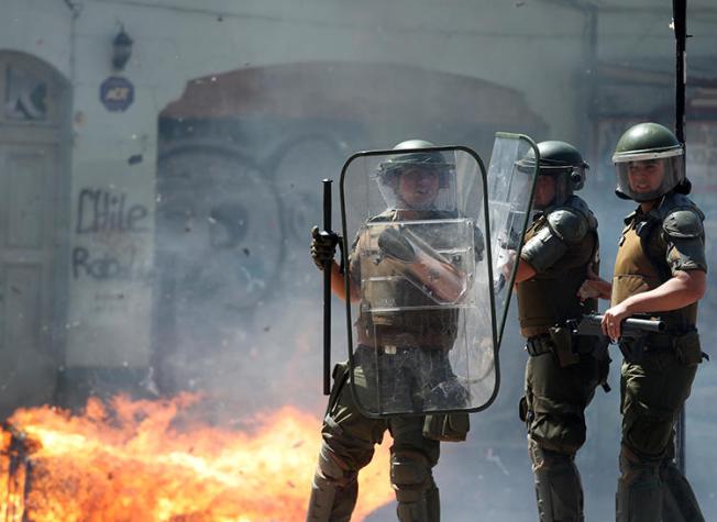 Imagen de agentes policiales frente a una barricada en llamas en Valparaíso, Chile, el 26 de noviembre de 2019. Las oficinas en Valparaíso del diario chileno El Líder fueron saqueadas e incendiadas por manifestantes el 26 de noviembre. (Reuters/Goran Tomasevic)