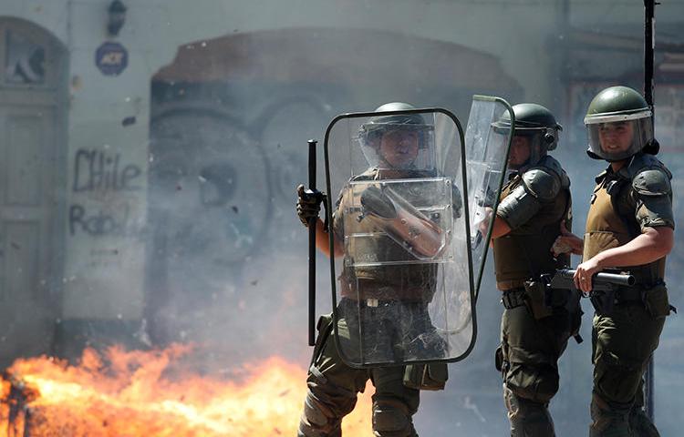 Imagen de agentes policiales frente a una barricada en llamas en Valparaíso, Chile, el 26 de noviembre de 2019. Las oficinas en Valparaíso del diario chileno El Líder fueron saqueadas e incendiadas por manifestantes el 26 de noviembre. (Reuters/Goran Tomasevic)