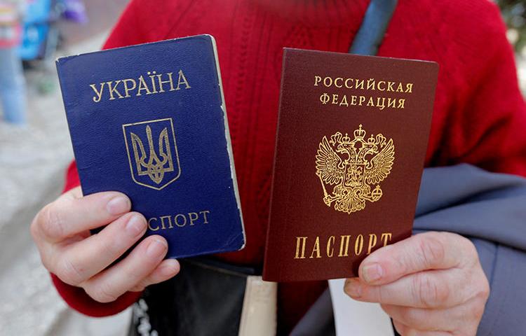 A woman poses with a Ukrainian and a Russian passport in the Crimean city of Simferopol on April 7, 2014. Ukrainian journalist Taras Ibragimov was recently barred from entering Crimea and was banned from entering Russia for 34 years. (Reuters/Maxim Shemetov)