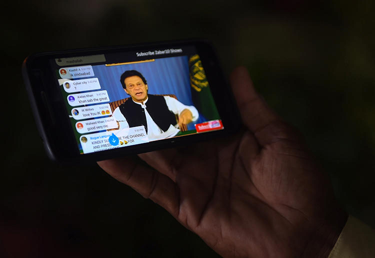 A Pakistani man watches a broadcast by Prime Minister Imran Khan on a smartphone in August 2018. Pakistani regulators are moving to regulate internet videos in measures that journalists fear will result in censorship or penalties. (AFP/Rizwan Tabassum)