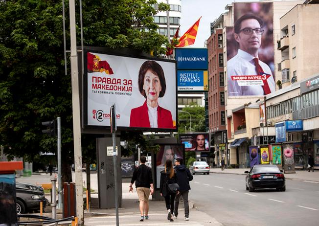 People walk under political billboards in Skopje, North Macedonia, on May 4, 2019. A North Macedonian government official recently threatened two journalists. (AFP/Robert Atanasovski)