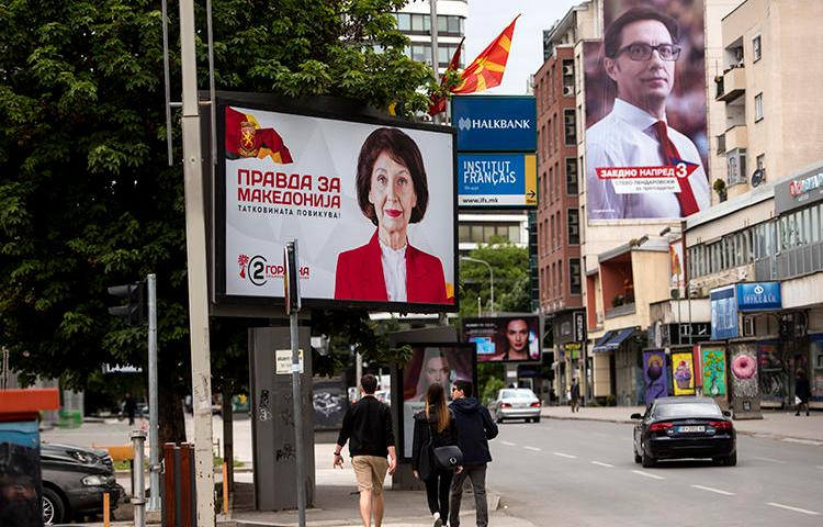 People walk under political billboards in Skopje, North Macedonia, on May 4, 2019. A North Macedonian government official recently threatened two journalists. (AFP/Robert Atanasovski)