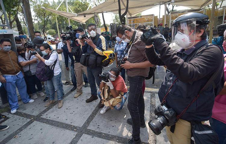 Mexican journalists, wearing personal protective equipment amid the COVID-19 pandemic, cover a protest by administrative workers at the General Balbuena Hospital in Mexico City on April 16, 2020. (AFP/Pedro Pardo)