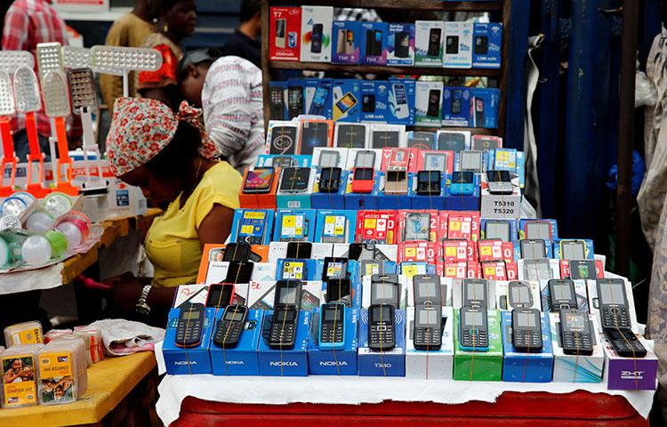 A woman vendor waits for customers as she uses her phone at the 'Computer Village' in Ikeja district in Nigeria's commercial capital Lagos on May 31, 2017. Nigeria’s police have used telecom surveillance to lure and arrest journalists. (Reuters/Akintunde Akinleye)