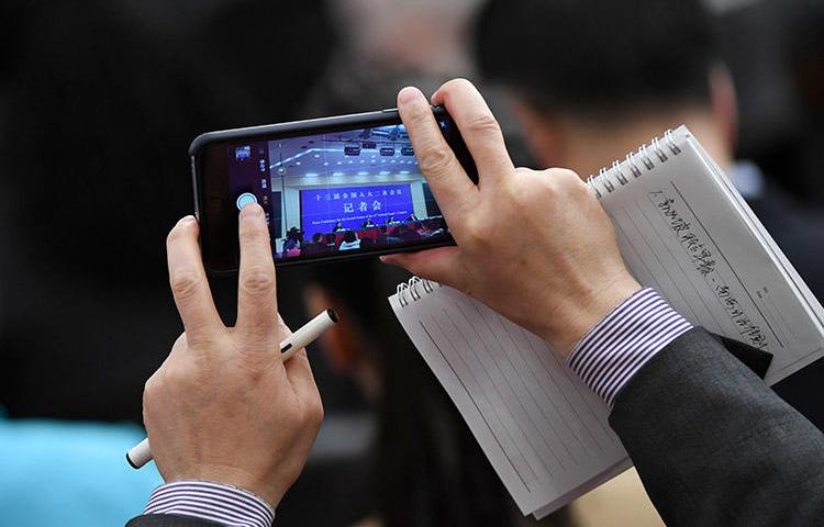 A journalist uses a phone to take photos during a National People's Congress press conference in Beijing in March 2019. The Foreign Correspondents' Club of China annual survey finds conditions for the foreign press deteriorated in 2019. (AFP/Wang Zhao)
