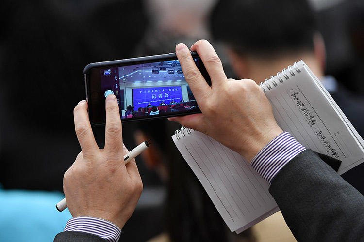 A journalist uses a phone to take photos during a National People's Congress press conference in Beijing in March 2019. The Foreign Correspondents' Club of China annual survey finds conditions for the foreign press deteriorated in 2019. (AFP/Wang Zhao)