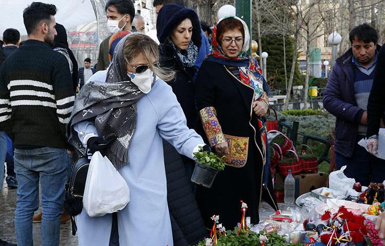 An Iranian woman wearing a protective face mask chooses traditional items ahead of Nowruz, the national New Year celebration, at the Tajrish Bazaar in the capital Tehran on March 19, 2020, despite the heavy death toll due the novel coronavirus in the country. Amid the coronavirus pandemic, the government has covered up crucial information and threatened journalists. (AFP/Stringer)