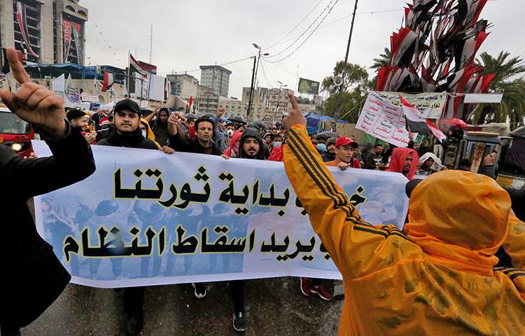 Iraqi protesters lift a banner n Tahrir Square in the capital Baghdad on February 25, 2020, amid renewed anti-government demonstrations. An Iraqi journalist was kidnapped in Baghdad on March 9. (AFP/Sabah Arar)