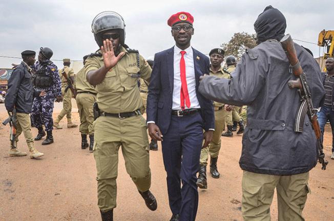 Ugandan opposition politician and popular musician Robert Kyagulanyi, also known as Bobi Wine (C), is escorted by a police officer as he is arrested on charges of unlawful assembly before starting his first public meeting ahead of presidential election next year, on January 6, 2020, in Kasangati town, a suburb of Kampala. Ugandan journalist Moses Bwayo was charged with illegal assembly and held in prison on March 4. (AFP/Stringer)