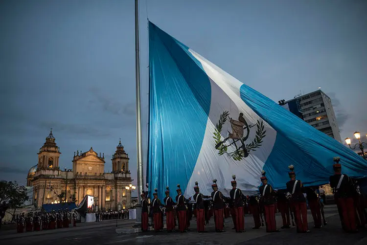 Soldados guatemaltecos izan la bandera nacional en la Plaza de la Constitución, Ciudad de Guatemala, en septiembre de 2019. Con la toma de posesión de un nuevo mandatario, el país tiene la oportunidad de mejorar las condiciones para el ejercicio del periodismo. (AP/Oliver de Ros)