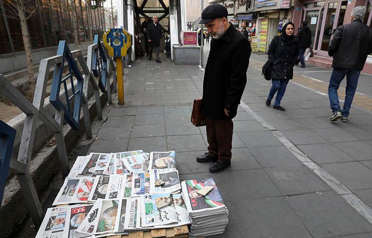 A man reads newspapers in Tehran, Iran, on January 4, 2020. The country recently banned all newspaper printing and distribution, citing fears of spreading COVID-19. (AP/Vahid Salemi)