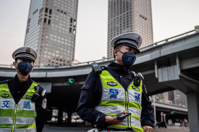 Police officers stand at a street crossing in Beijing, China, on April 7, 2020. Beijing police recently arrested documentary filmmaker Chen Jiaping on subversion charges. (AFP/Nicolas Asfouri)